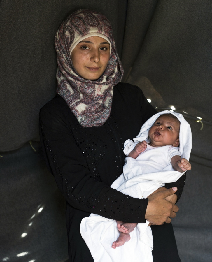 19-year-old Farah Sheikh Ahmed a Syrian mother from the city of Idlib, poses with her baby girl Maram in a tent made of blankets given by the UNCHR at the refugee camp of the northern Greek border point of Idomeni.