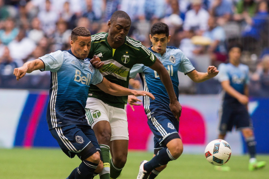 Vancouver Whitecaps' Erik Hurtado, left, fights for the ball against Portland Timbers' Fanendo Adi, center, during the second half of an MLS soccer game in Vancouver, British Columbia, Saturday, May 7, 2016.