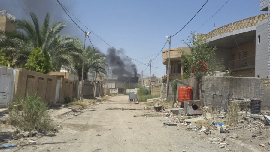 A street is deserted Tuesday in Fallujah, Iraq, as smoke rises from fighting between Iraqi counterterrorism forces and Islamic State militants in the southern part of the city.