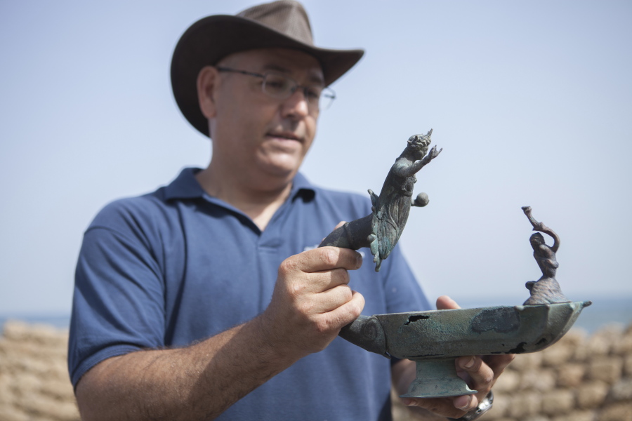 Jacob Sharvit of the Israel Antiquities Authority holds a bronze lamp depicting the image of a Roman sun god Monday in Caesarea, Israel.