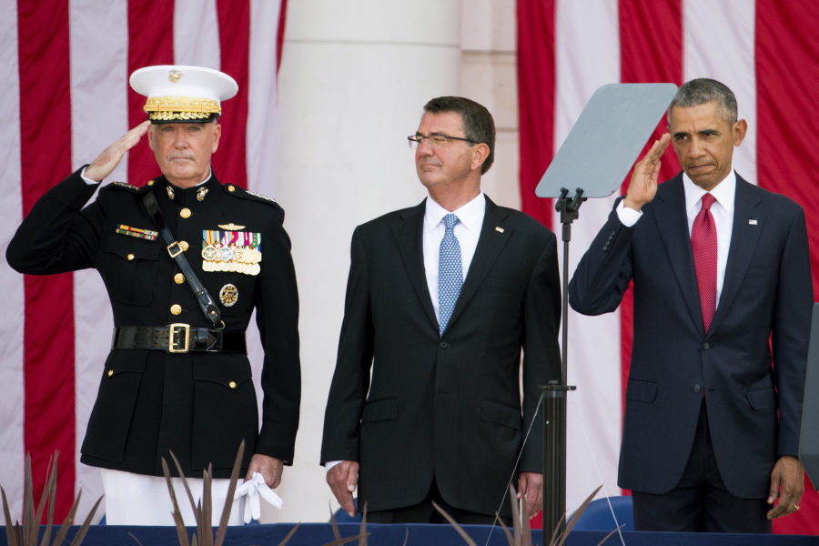 President Barack Obama, right, accompanied by Defense Secretary Ash Carter, center, and Joint Chiefs Chairman Gen. Joseph Dunford, left, salutes a member of the audience as he arrives to speak at the Memorial Amphitheater of Arlington National Cemetery, in Arlington, Va., on Monday during a Memorial Day ceremony.