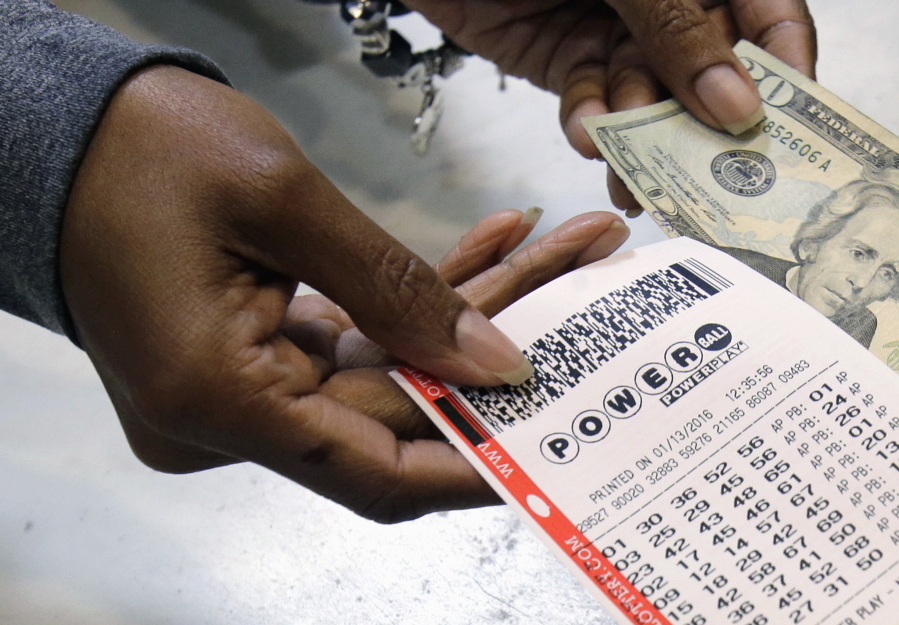 A clerk hands over a Powerball ticket Jan. 13 at Tower City Lottery Stop in Cleveland. Powerball estimates that its jackpot for the May 7 drawing is $415 million.