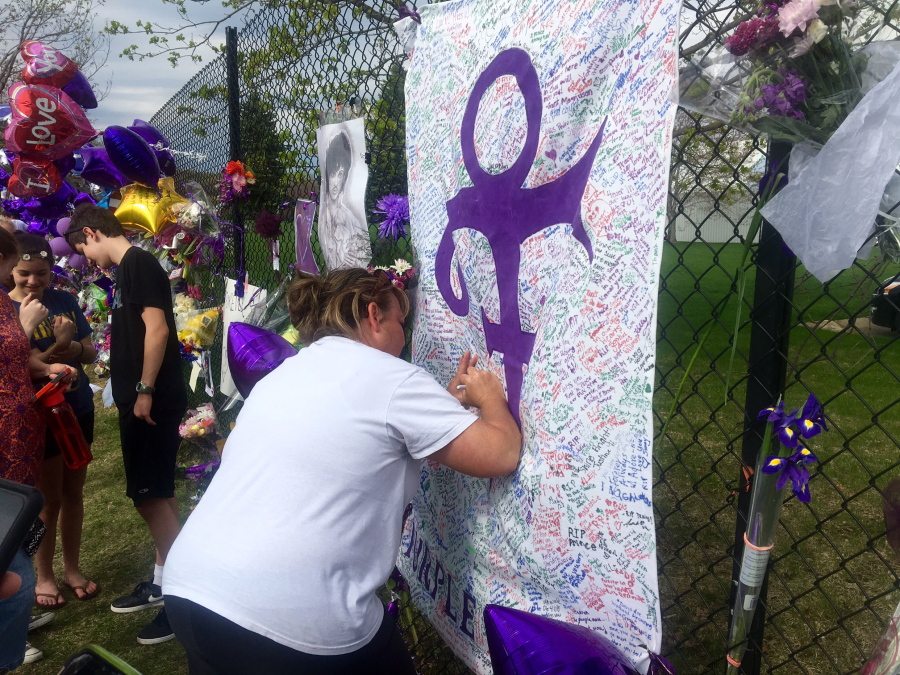 A woman writes on memorial sheet adorned with the symbol Prince once used to identify himself outside Paisley Park in Chanhassen, Minn., on Saturday. The music superstar was pronounced dead at his Paisley Park estate near Minneapolis on Thursday. He was 57.