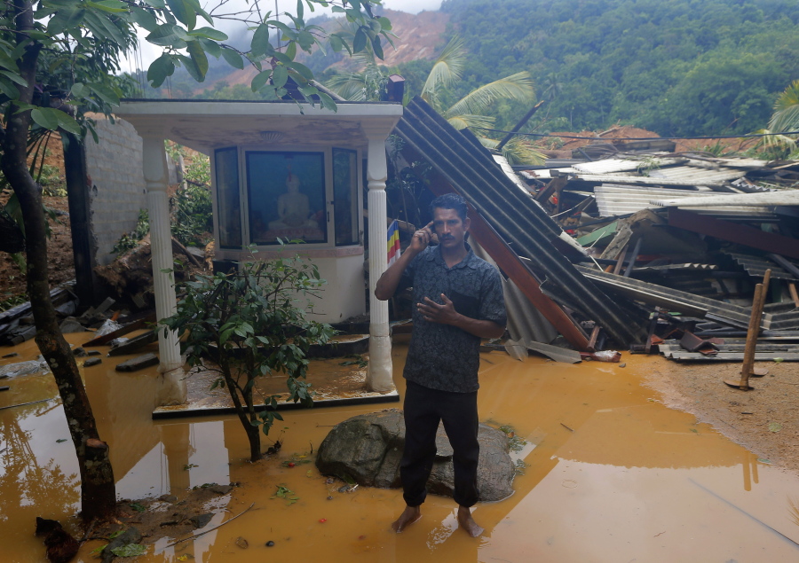 A man whose relatives are missing speaks on his phone Thursday in front of a destroyed house in Elangapitiya village, Sri Lanka. Heavy rains continued to pound the region where at least three villages have been covered by mudslides.