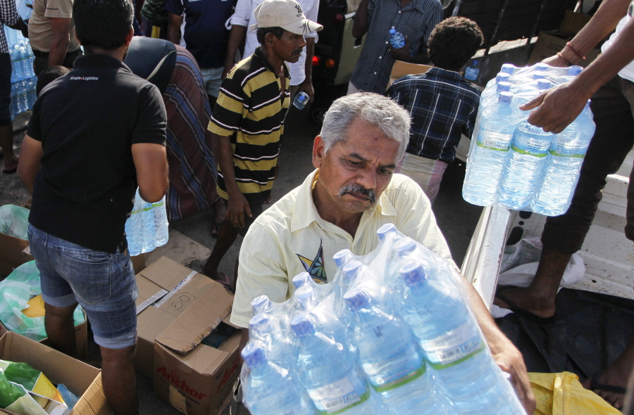 Sri Lankan volunteers unload bottles of drinking water  for distributing to the flood victims in Wellampitiya on the out skirts of Colombo, Sri Lanka, on Friday.