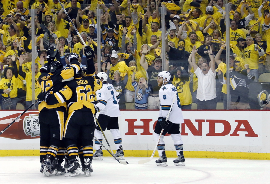 Pittsburgh Penguins&#039; Ben Lovejoy (12) and Carl Hagelin (62) swarm Nick Bonino after his game-winning goal against the San Jose Sharks during the third period in Game 1 of the Stanley Cup final series Monday, May 30, 2016, in Pittsburgh.
