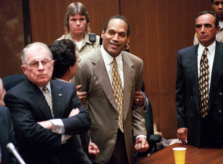 O.J. Simpson, center, clenches his fists in victory in October 1995 after the jury said he was not guilty in the murders of his ex-wife Nicole Brown Simpson and her friend Ronald Goldman in a Los Angeles courtroom, as attorneys F. Lee Bailey, left, and Robert Shapiro, right, look on.