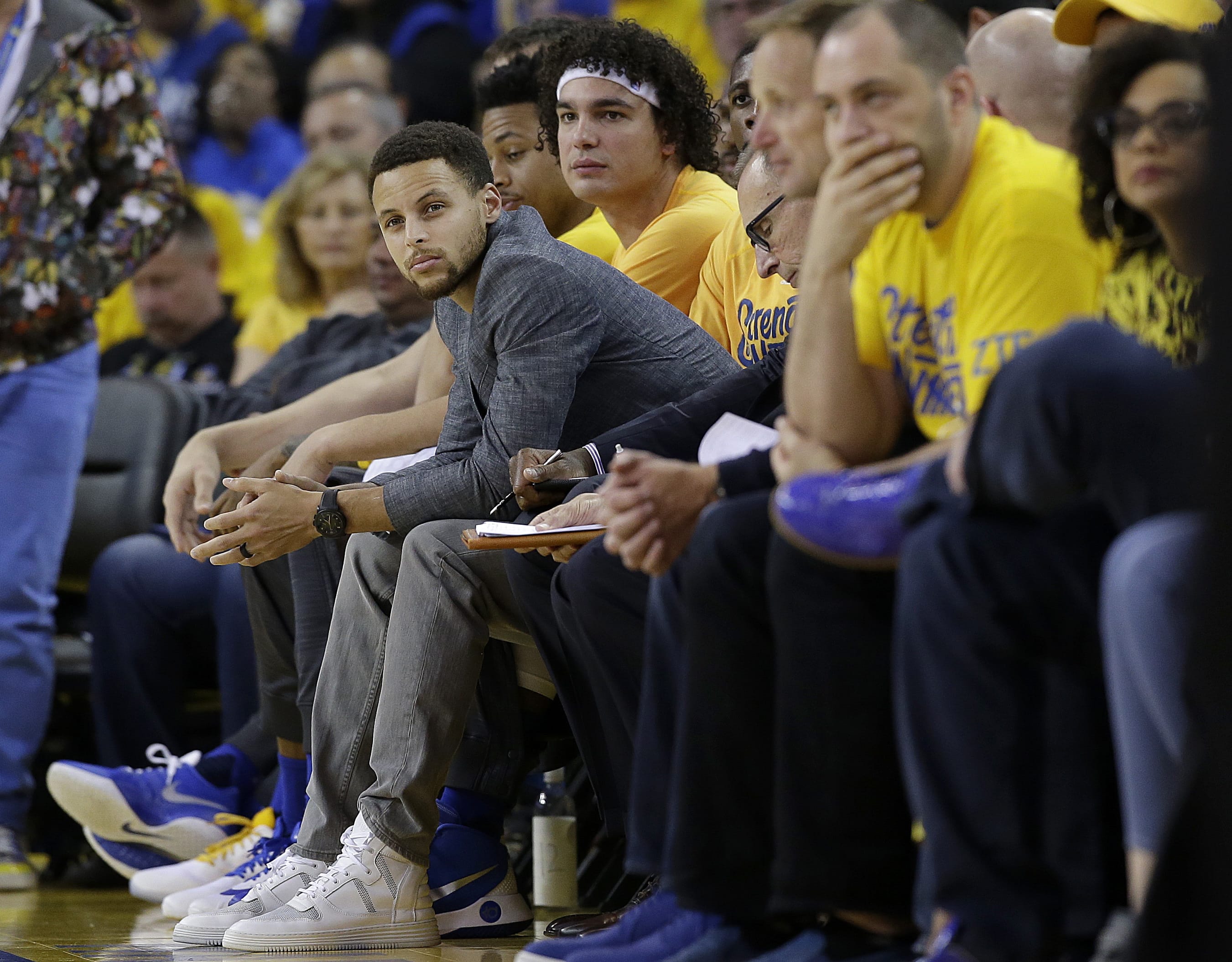 Golden State Warriors guard Stephen Curry, center left, sits on the bench during the first half in Game 2 of a second-round NBA basketball playoff series between the Warriors and the Portland Trail Blazers in Oakland, Calif., Tuesday, May 3, 2016.