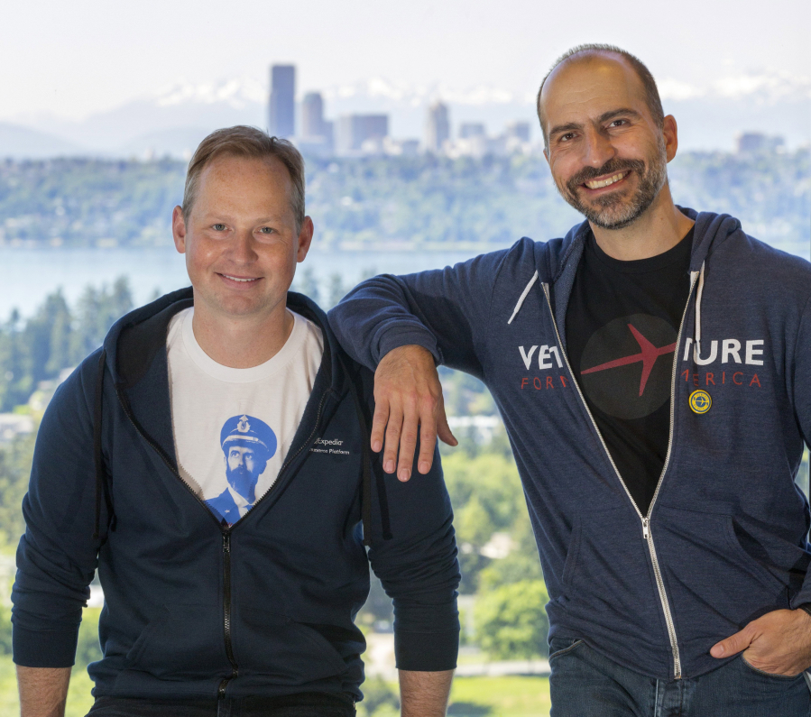 Expedia&#039;s Dara Khosrowshahi, right, and Mark Okerstrom discuss the online travel company&#039;s future on May 11 at its Bellevue offices. Expedia plans to move its headquarters to Seattle, whose skyline looms in the distance.