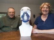 Vicki and Norman Paulk on Wednesday demonstrate the CPAP mask cover they designed at their home in Camas. Norman, who suffers from sleep apnea, invented a soft fabric guard to help make wearing the oxygen mask for an extend period of time more comfortable.