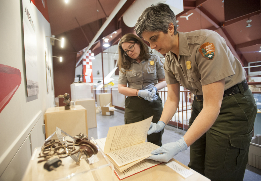 Meagan Huff, left, and curator Theresa Langford look through a log book for an appropriate page to display in the new Pearson Air Museum exhibit highlighting the 1937 Chkalov flight.