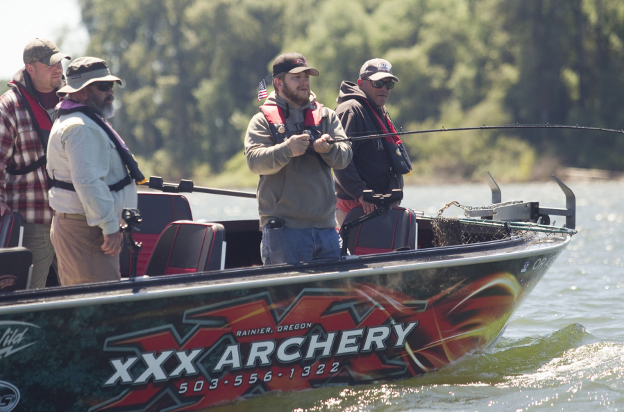 Veteran Jason Royse reels in a line Sunday morning during Operation Salmon Salute near Ridgefield. Royse is joined by other veterans, from left, Matt Wirkkla, Anthony Cavenaugh and Jason Dodge.