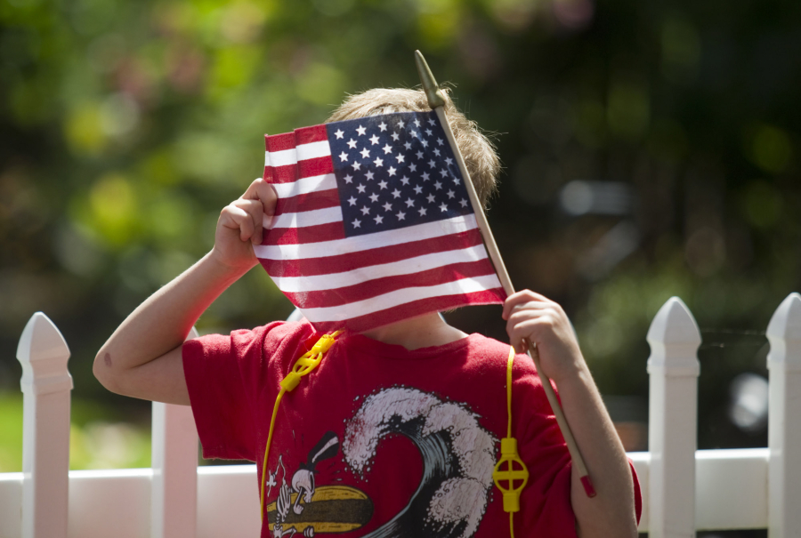 A little boy looks through the fabric of his American flag as he attends an Independence Day parade in Ridgefield.