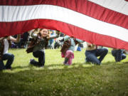 Mikaela Fisher, a member of Brownie Girl Scout Troop 45722, helps support a huge American flag during Fort Vancouver's Flag Day celebration in 2017.