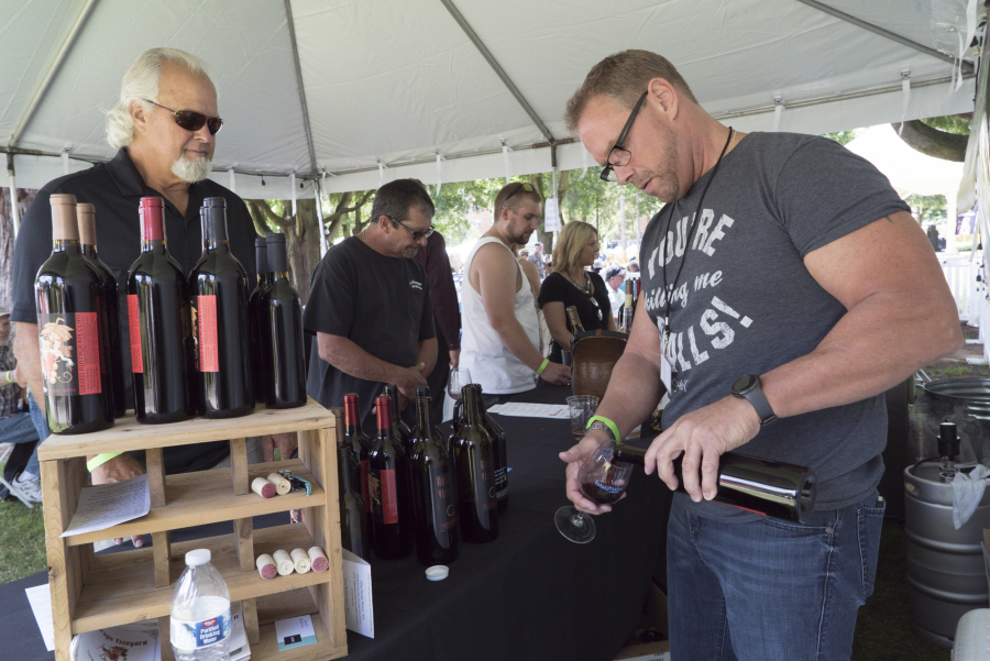 Gary Nylander of Vancouver, left, waits while Rick Nuttail pours him a glass of wine at the Rusty Grape Vineyard booth Sunday at the Craft Beer and WineFest of Vancouver in Esther Short Park.