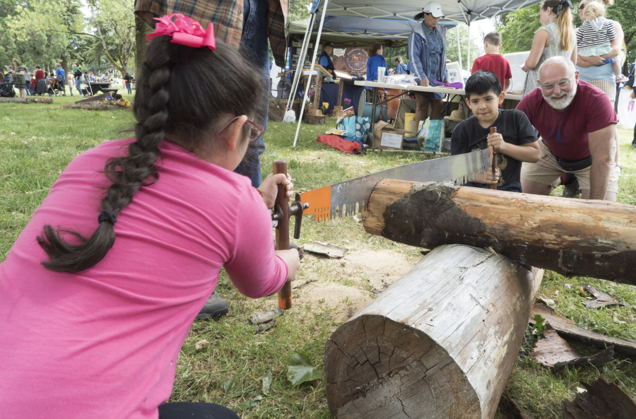 Valerie Rodriguez, 7, left, and brother Jonathan, 10, of Beaverton, Ore., cut a log with the help of Jeff Booth, a volunteer with the Pacific Crest Trail Association, Saturday at Fort Vancouver&#039;s National Get Outdoors Day festivities. Valerie and Jonathan came with their uncle Manny Rodriquez and his family, who live in Vancouver.