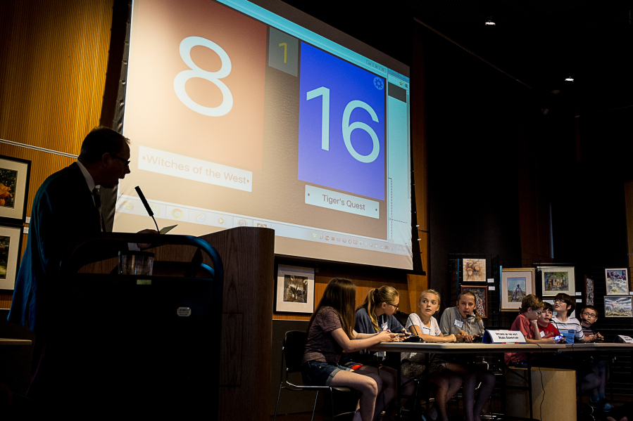 Competition moderator Mark Ray asks a question to the Witches of the West and Tiger&#039;s Quest teams during the Vancouver Public School District Battle of the Books at the Vancouver Community Library on Saturday.