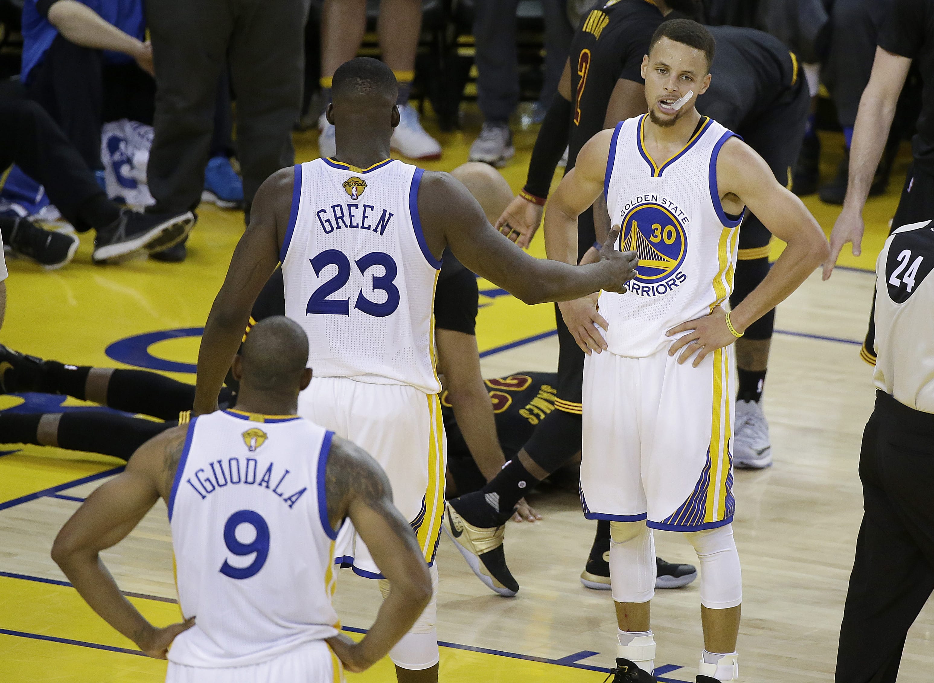 Golden State Warriors guard Stephen Curry (30), forward LeBron James (23) and forward Andre Iguodala (9) stand on the court as Cleveland Cavaliers forward LeBron James, on ground, is tended to during the second half of Game 7 of basketball's NBA Finals in Oakland, Calif., Sunday, June 19, 2016. The Cavaliers won 93-89.