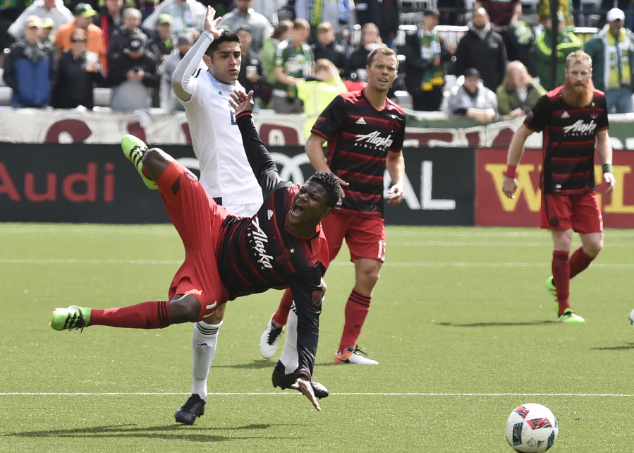 Portland Timbers forward Dairon Asprilla (11) is tripped by Vancouver Whitecaps midfielder Matias Laba, back left, during the second half of an MLS soccer game in Portland, Ore., on Sunday, May 22, 2016.
