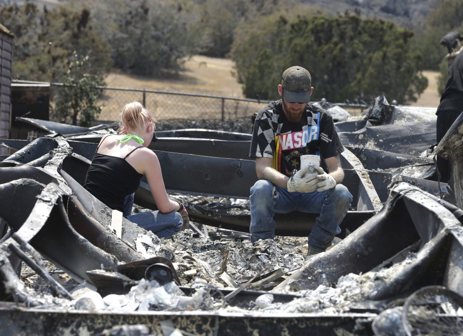 Lucas Martin stares at a cup found in the ashes of his fire-ravaged home Sunday in South Lake, Calif.. Martin&#039;s home was among the more than 200 homes and buildings destroyed by the fire that swept through the area near Lake Isabella, Calif. At left is Emily Fryer, who helped Martin sift through the rubble.