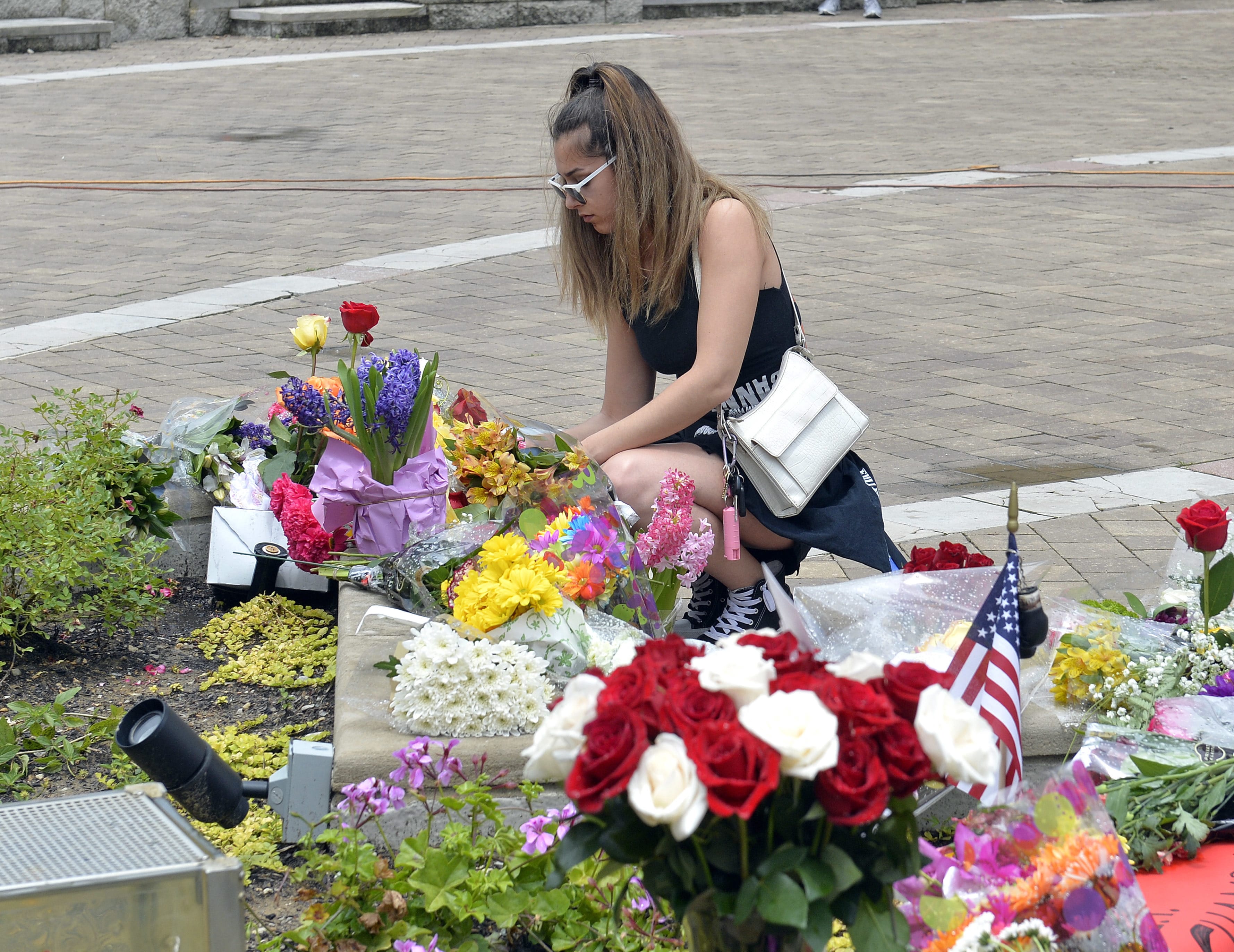 Vanessa Buzgheia, of Louisville, Ky., sets up flowers that were knocked over by the wind at a memorial to Muhammad Ali at the Muhammad Ali Center, Saturday, June 4, 2016 in Louisville Ky. Ali, the magnificent heavyweight champion whose fast fists and irrepressible personality transcended sports and captivated the world, has died according to a statement released by his family Friday, June 3. He was 74. (AP Photo/Timothy D.