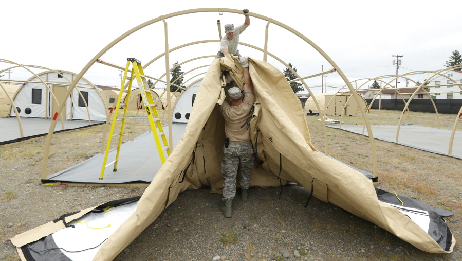 In this photo taken May 24, 2016, Staff Sgt. Andrew Waddell, top, and Master Sgt. Tyler Bates, bottom, both of the Washington Air National Guard based at Fairchild Air Force Base in Spokane, Wash., work to assemble temporary living structures at Joint Base Lewis-McChord in Washington state that will be used by troops taking part in a massive earthquake and tsunami readiness drill overseen by the Federal Emergency Management Agency on June 7-10, 2016. (AP Photo/Ted S. Warren) (Photos by Ted S.