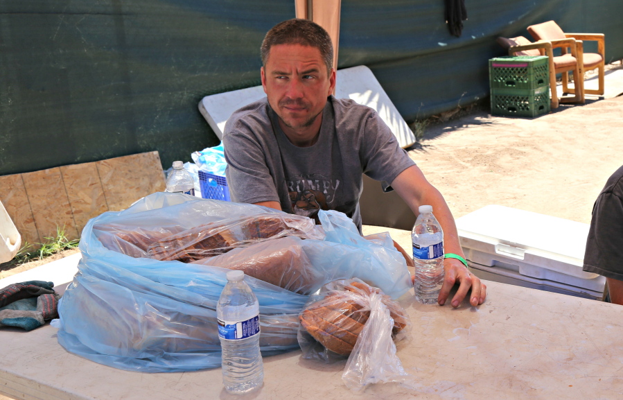 Mike Mcfarland, a volunteer at Redeemed Outreach Center, passes out free water bottles and bread to people who walk by Tuesday in downtown Phoenix, Ariz. The center of is one of 50 water cooling stations setup up around Maricopa County to help people stay cool in the summer heat.