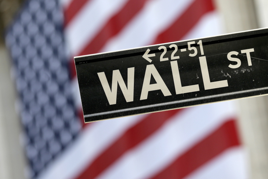A Wall Street street sign is framed by an American flag hanging on the facade of the New York Stock Exchange.