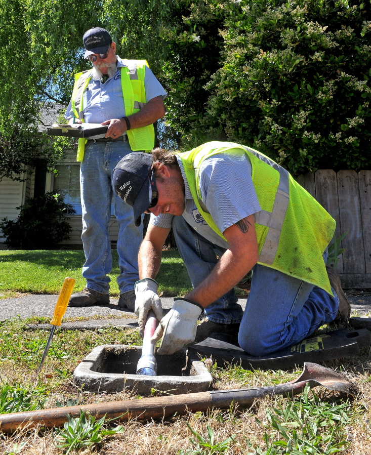 Creighton Nevin, front, and Joe Watson, both of the Medford Water Commission, check meters for galvanized pipe that may contain lead connectors Monday in Medford, Ore.