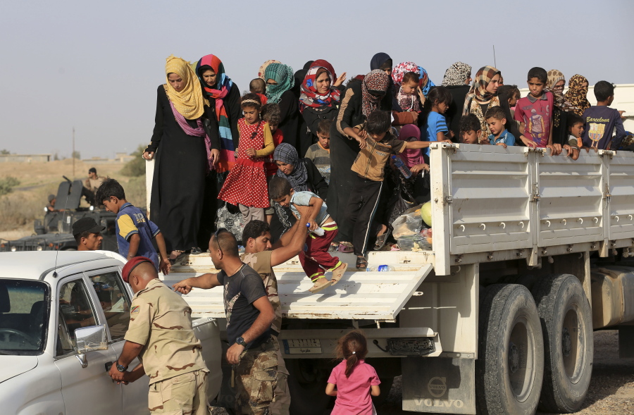 Iraqi soldiers help displaced families from a vehicle outside an Iraqi army military camp Friday near Fallujah, Iraq.
