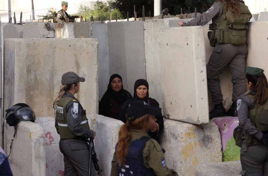 Palestinian women walk through a cement-block barrier Friday at an Israeli checkpoint in Bethlehem on their way to attend prayers in Jerusalem&#039;s al-Aqsa mosque.
