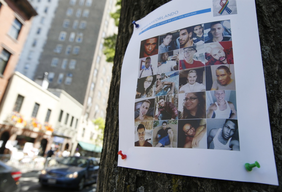 A sign with photos of victims of the Orlando nightclub shootings is tacked to a tree across the street from the Stonewall Inn, birthplace of the modern gay rights movement where there is a makeshift memorial to the Orlando victims on Wednesday in New York.