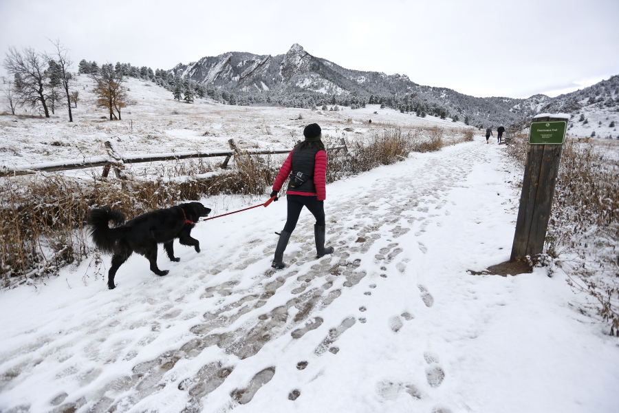 A woman walks her dog into local open space wildland at Chautauqua Park, in Boulder, Colo.