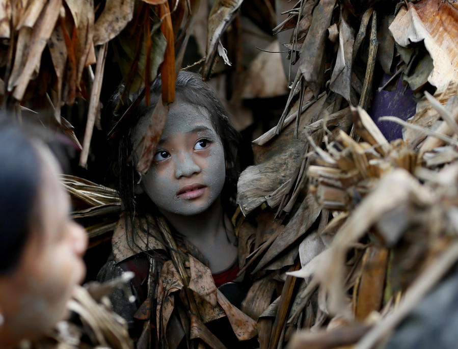 A village girl, in a cape mostly of dried banana leaves and covered in mud, attends Mass in an annual ritual to venerate her village&#039;s patron saint, John the Baptist, Friday, June 24, 2016 at Bibiclat, Aliaga township, Nueva Ecija province in northern Philippines. The &quot;Taong Putik&quot; or &quot;mud people&quot; festival in Bibiclat village dates back to the Japanese occupation of the Philippines in the 1940s.