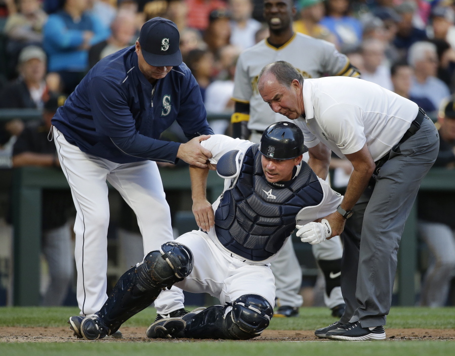 Seattle Mariners catcher Steve Clevenger, center, is helped to his feet by manager Scott Servais, left, and trainer Rick Griffin after Clevenger was injured during the third inning of a baseball game against the Pittsburgh Pirates on Wednesday, June 29, 2016, in Seattle. Clevenger left the game.