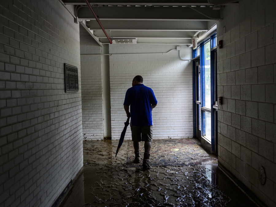 Principal Mike Kelley walks through a hallway that is filled with slick mud at Herbert Hoover High School in Clendenin, W.Va., on Monday. The first floor hallways and rooms of the school are caked in 3-5 inches mud, which was left by over six feet of flood water that swamped the building late last week.