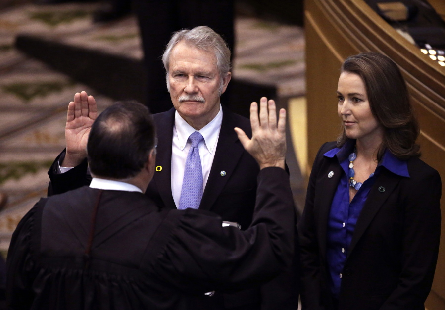 Oregon Gov. John Kitzhaber, left, is joined by his fiancee, Cylvia Hayes, as he is sworn in for an unprecedented fourth term in Salem, Ore., in January 2015. In the wake of a unanimous decision by the U.S. Supreme Court to vacate a corruption conviction against former Virginia Gov. Bob McDonnell, legal experts say federal prosecutors in Oregon face a narrowed scope in influence-peddling cases like the one involving Kitzhaber. Kitzhaber has been under federal investigation for a scandal involving Hayes, who worked as a paid environmental consultant while advising the former governor on environmental policy.