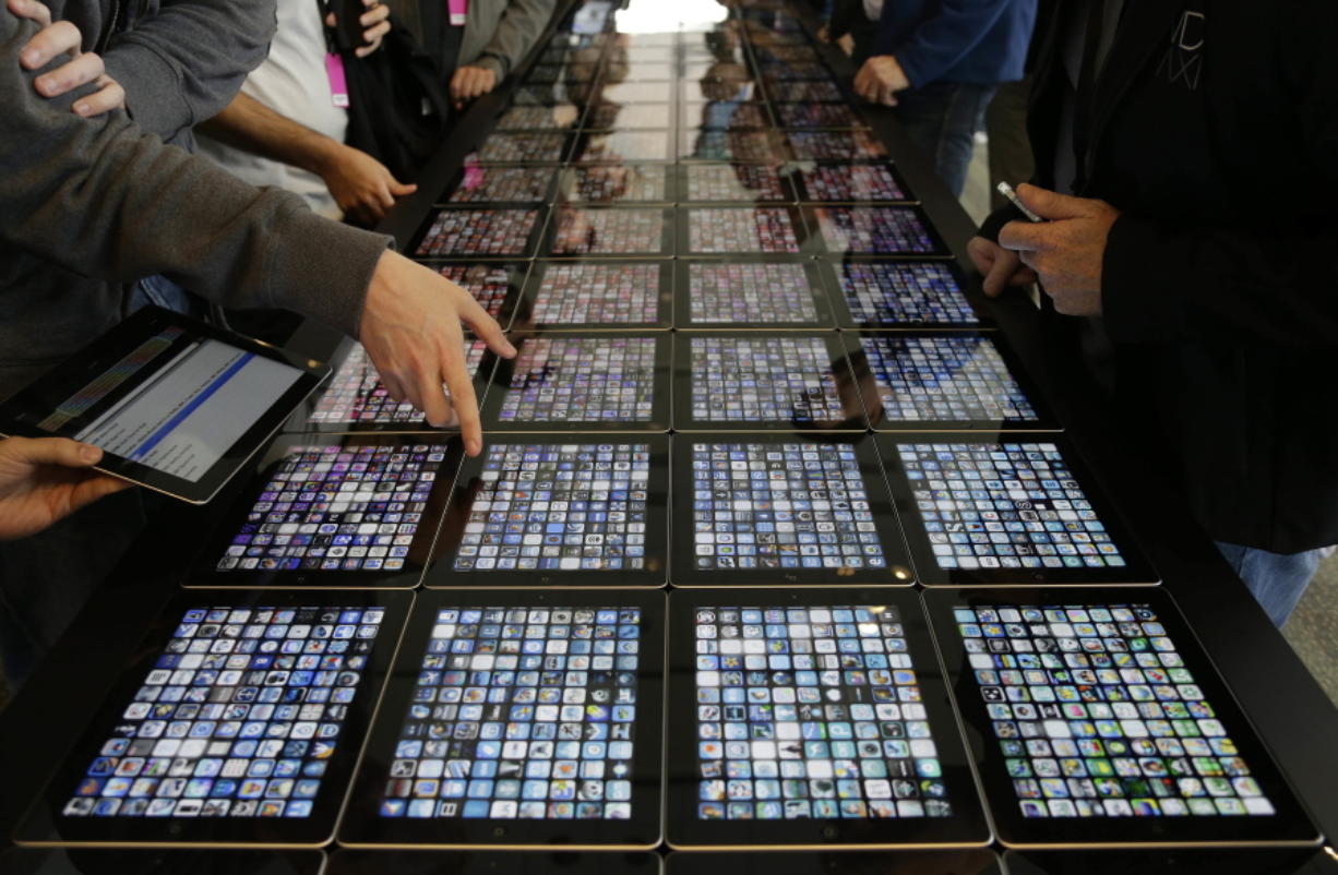 Developers look over new apps being displayed on iPads at the Apple Worldwide Developers Conference in San Francisco.