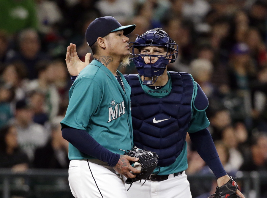 Seattle Mariners catcher Chris Iannetta, right, gives a pat to starting pitcher Felix Hernandez after a play during the third inning of a baseball game against the Minnesota Twins on Friday, May 27, 2016, in Seattle. Hernandez gave up five runs in the inning.
