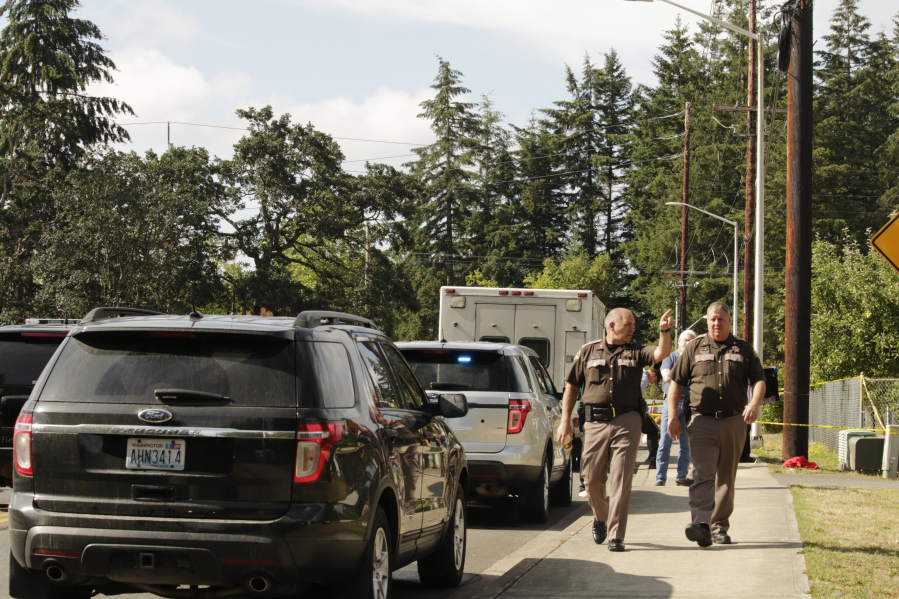 Officials with the Thurston County Sheriff&#039;s Office walk in a neighborhood where a shooting left multiple people dead Wednesday in Lacey. Police have not yet determined a suspect or motive.
