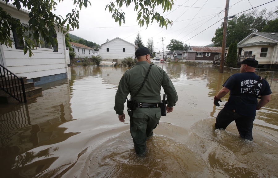 West Virginia State Trooper C.S. Hartman, left, and Bridgeport W. Va., fireman, Ryan Moran, wade through flooded streets as they search homes in Rainelle. A rainstorm that seemed no big deal at first turned into a catastrophe for the small town in West Virginia, trapping dozens of people whose screams would echo all night.