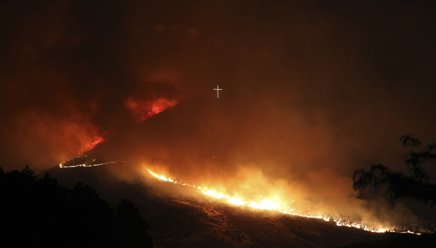 A wildfire burns near the Table Rock cross in Boise, Idaho in the early morning hours of Thursday, June 30, 2016. Strong winds pushed the fire around Table Rock and south toward Warm Springs Mesa subdivision and Harris Ranch, according to the Idaho Statesman.