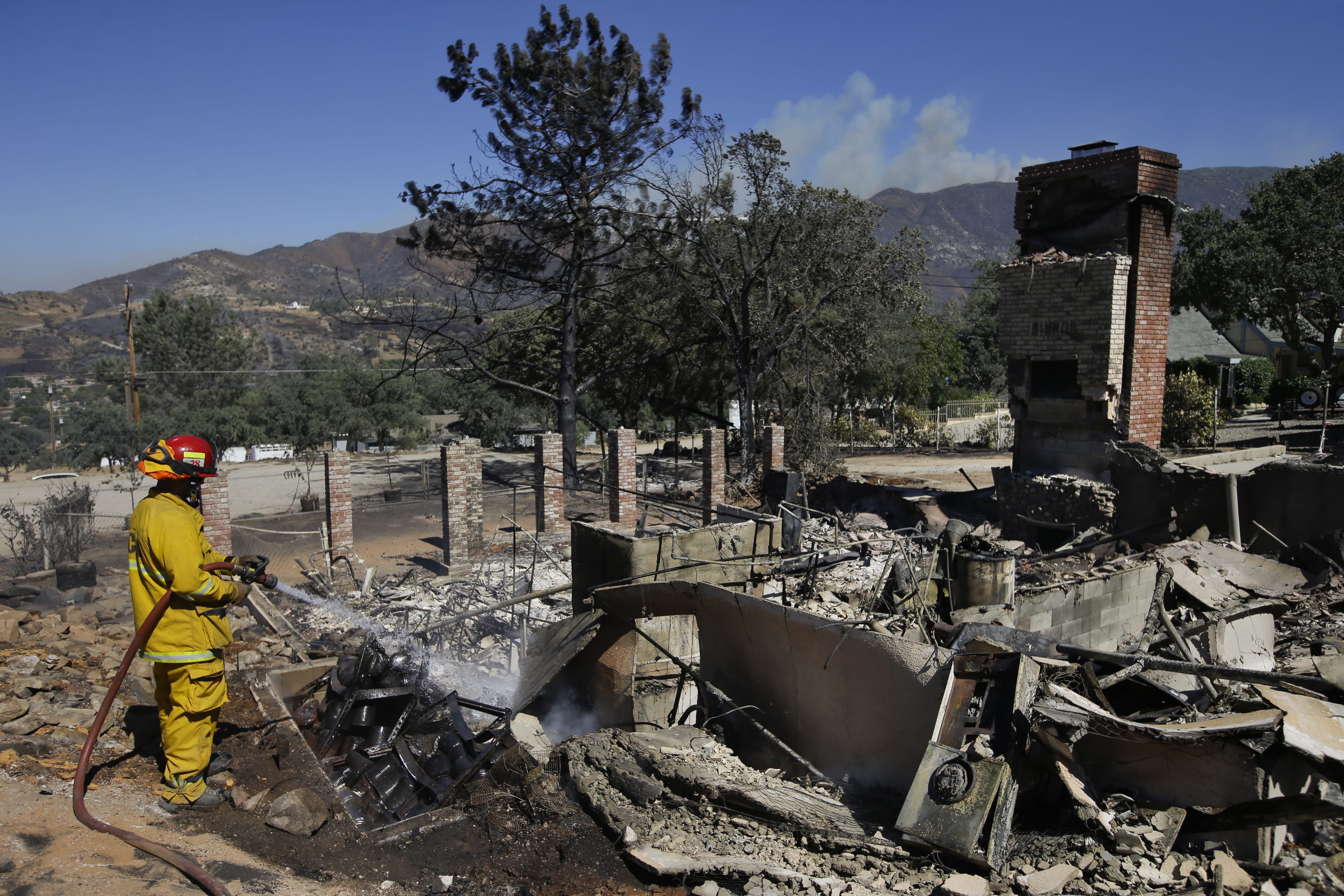 Firefighter Kyle Newton puts out a hotspot at a home scorched by a wildfire Friday, in Mountain Mesa, Calif. (Jae C.