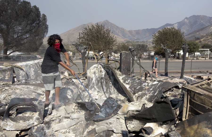 Aquivo Sun goes through the burned out remains of the home he shares with Brittany Thompson, right, Sunday in South Lake, Calif.