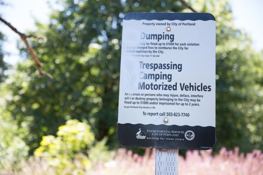 Someone has spray painted this city sign, posted at the entrance to a homeless camp on the Springwater Corridor bike path, so it no longer reads &quot;No Camping.&quot; (Photos by Amelia Templeton/OPB)