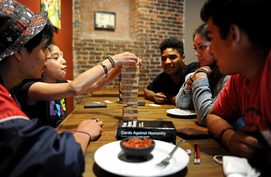 A group of young people play Tumbling Tower at the GameHaus Cafe in Glendale, Calif.