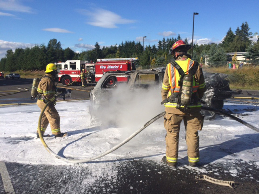 Firefighters from Fire District 3 work to extinguish a vehicle fire after a crash earlier this month on Highway 503. The district&#039;s board is asking voters to approve funding for two new firefighter-paramedics.