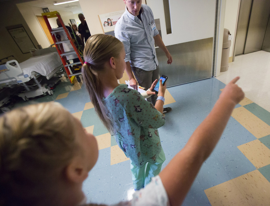 Tyler Medick, Harborview Medical Center research assistant in Rehabilitation Medicine, supervises Priscilla Wagoner, center, and her twin sister, Olivia, as they hunt for Pokemon.