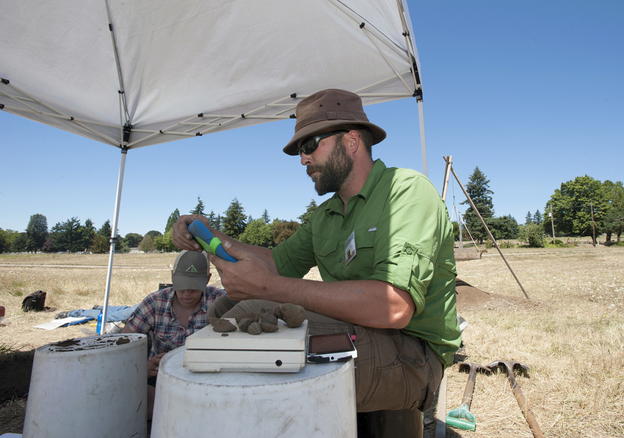 James Ficek, Washington State University Vancouver senior, weighs and measures fire-cracked rock Wednesday while working with Portland State University senior Paula Hale at Fort Vancouver National Historic Site.