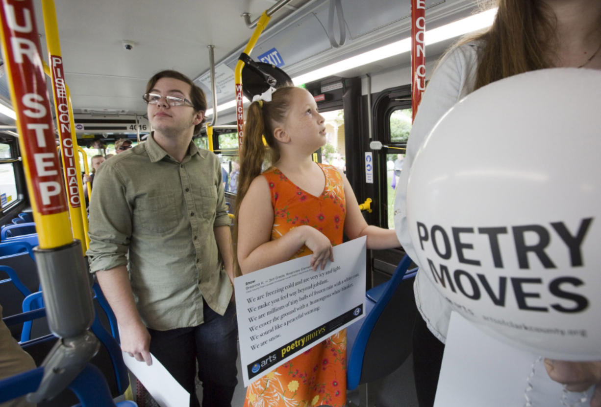 Fort Vancouver High School student Cole Beckman, left,  and Riverview Elementary School student Breanna Kelley, center, look Sunday at student poems, including their own, that will be displayed in C-Tran buses.